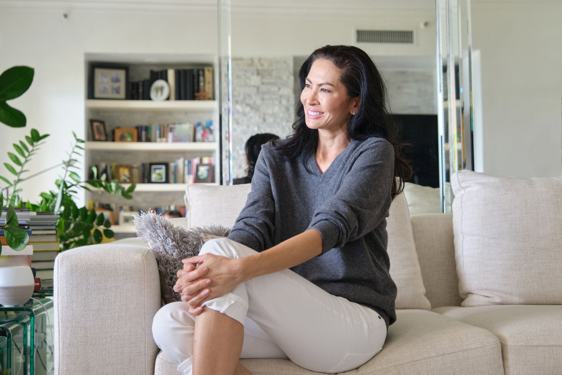 Woman in her forties sitting comfortably on a couch at home, smiling