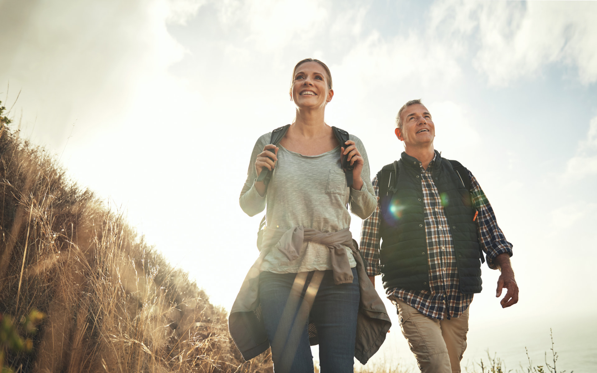 Smiling midlife couple hiking outdoors in golden evening light